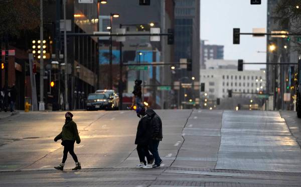 Pedestrians wear masks while crossing an empty road at the intersection of Market Street and 15 ...