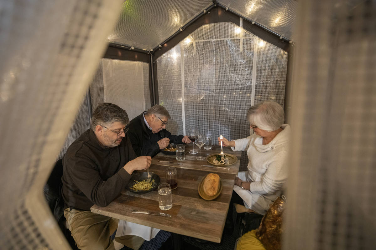 Adam Winer, left, Howard Winer, center, and Charlotte Winer dine in a dining tent outside of Es ...