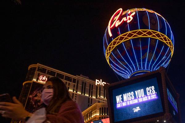 A masked pedestrian walks past a marquee at Paris that memorializes CES, which would have start ...