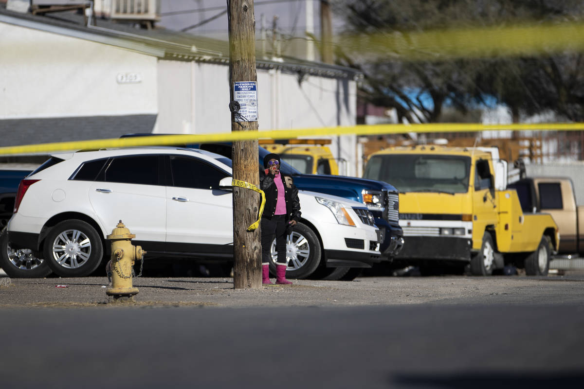 A bystander watches as police investigate the scene of a fatal shooting near the intersection o ...