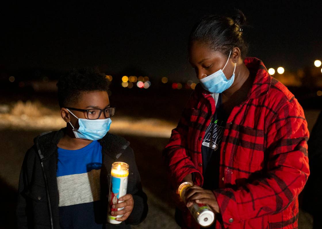 Jayden Felder, left, and his mother Ronita Felder light candles at a vigil for Eric Echevarria, ...