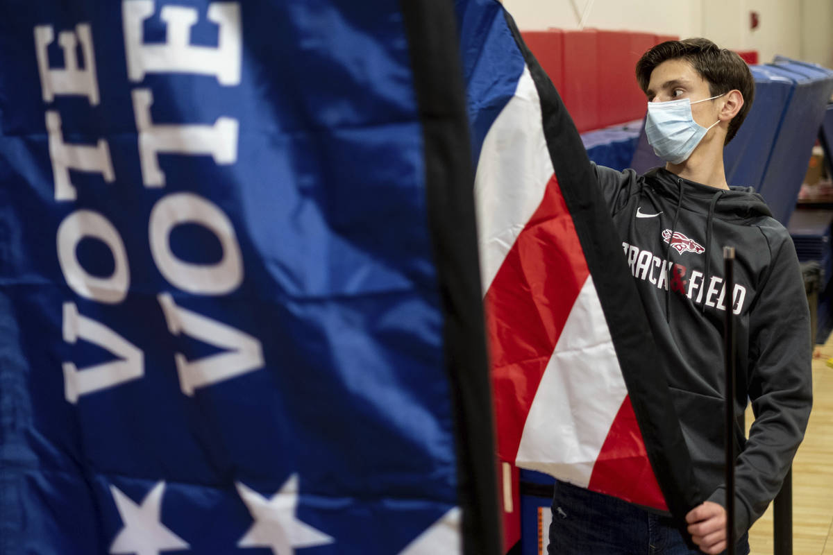 Thomas Hedrich sets up voting flags at a polling location in Gwinnett County, Ga., outside of A ...