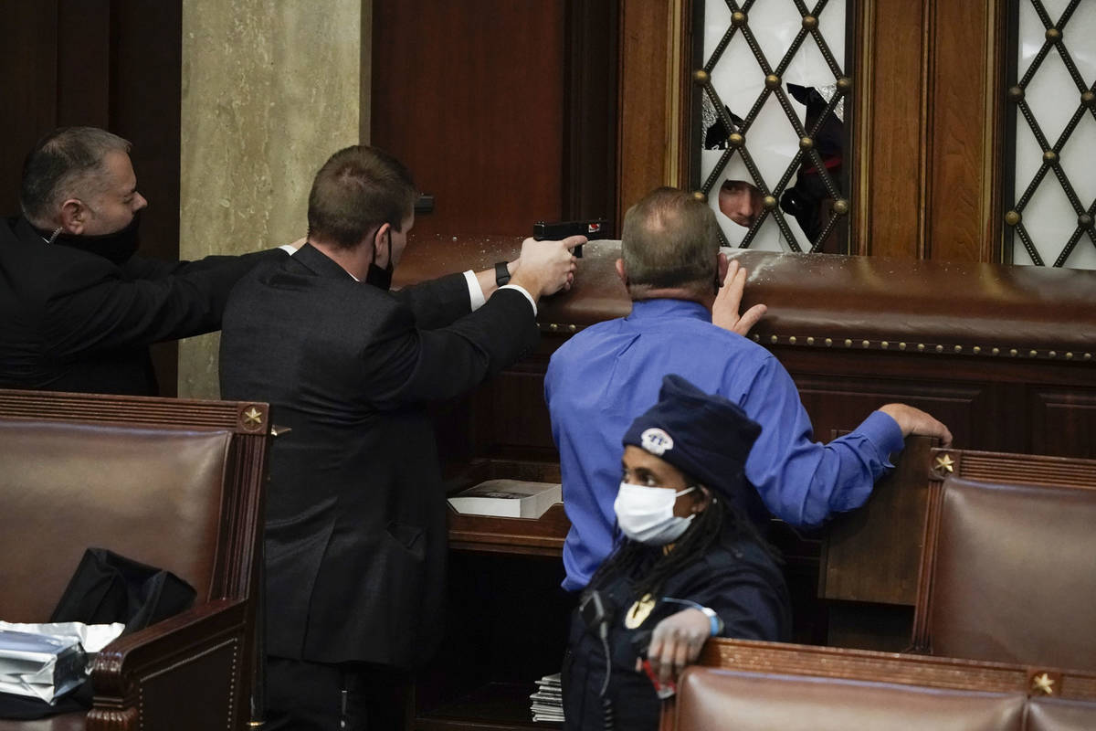 Police with guns drawn watch as protesters try to break into the House Chamber at the U.S. Capi ...