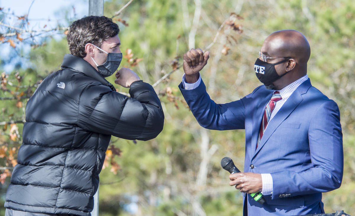 Jon Ossoff, left, and Raphael Warnock exchange elbow bumps during a campaign rally in Augusta, ...