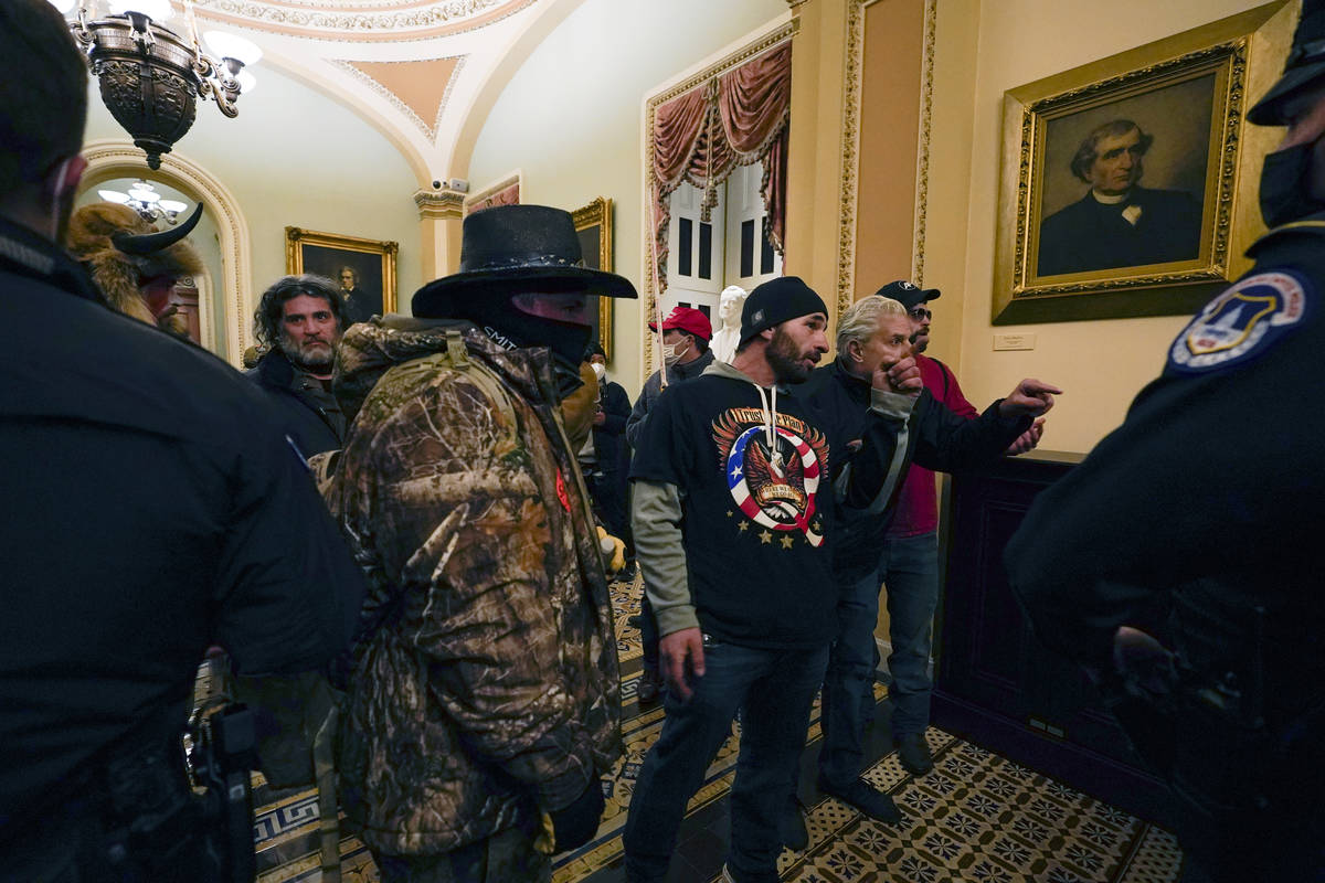 Protesters walk as U.S. Capitol Police officers watch in a hallway near the Senate chamber at t ...