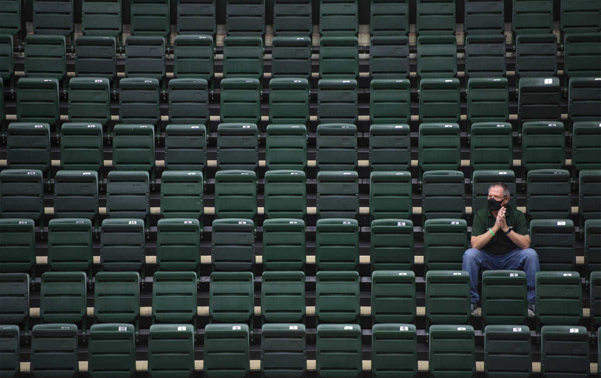 A lone spectator sits in the bleachers during the first half of an NCAA college basketball game ...