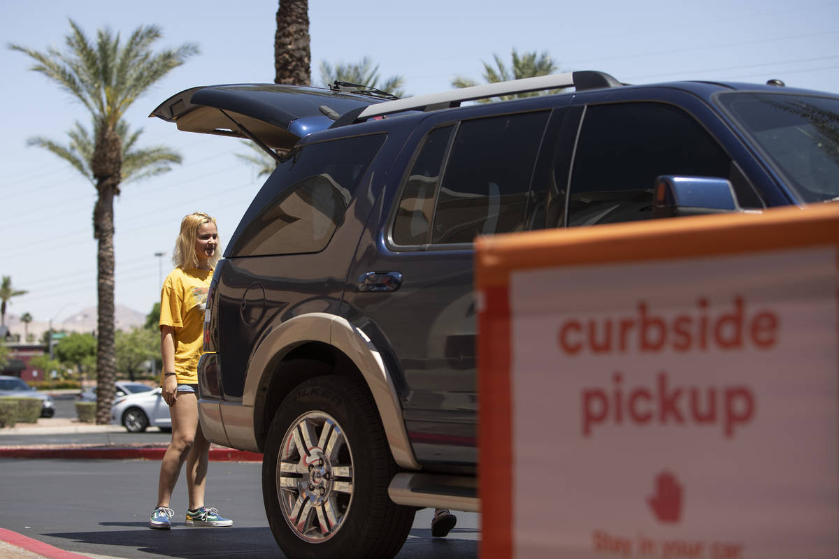 Kayla Walsh opens the trunk for an Ulta employee to put the curbside pickup order she and her m ...