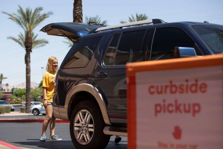 Kayla Walsh opens the trunk for an Ulta employee to put the curbside pickup order she and her m ...