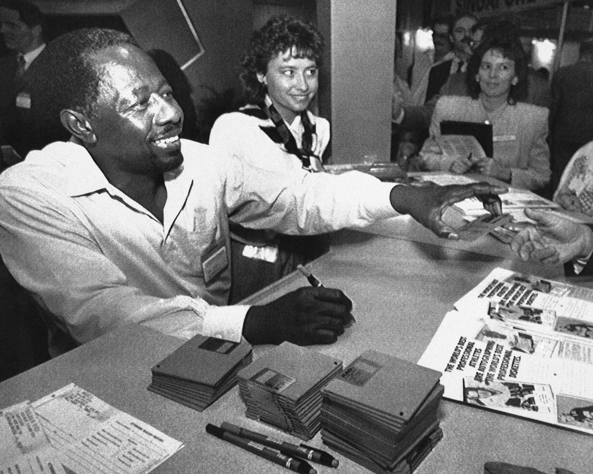 Former baseball great Henry Aaron signs autographs on computer disks at the Comdex convention i ...