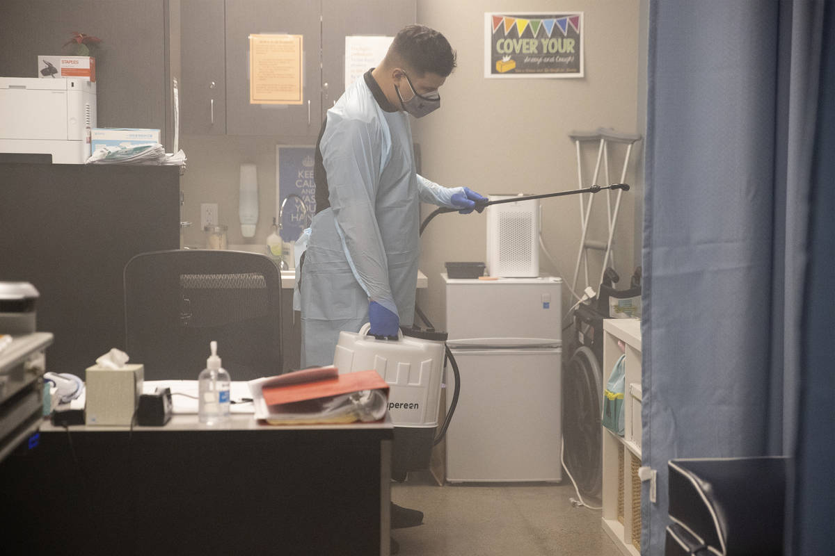 School custodian Gabriel Gonzalez sprays the nurse's office with a sanitizer at Mater Academy E ...