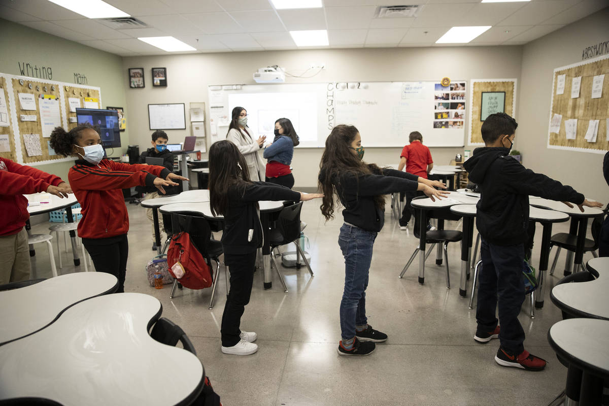 Students reach out with their arms to practice social distancing while walking to their next cl ...