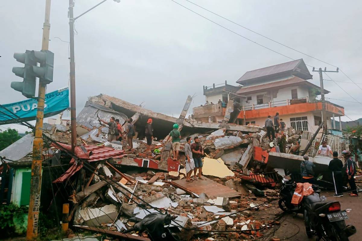 Residents inspect earthquake-damaged buildings in Mamuju, West Sulawesi, Indonesia, Friday, Jan ...