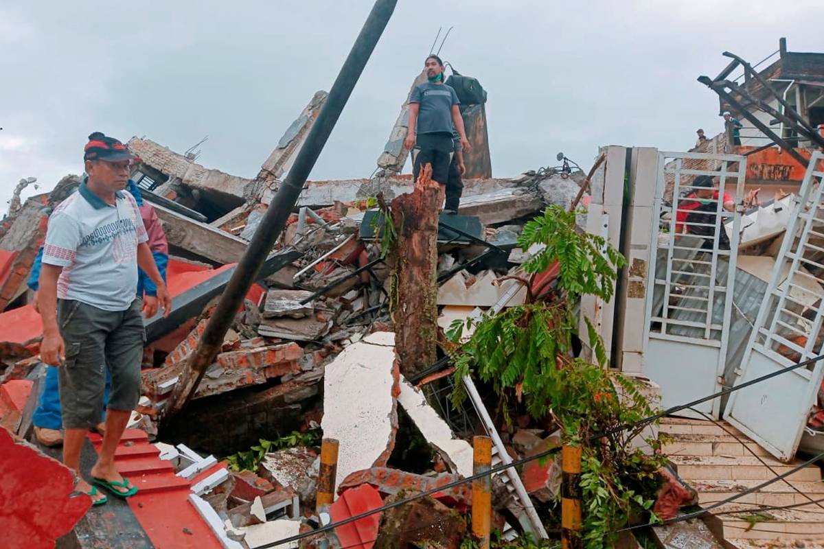 Residents inspect earthquake-damaged houses in Mamuju, West Sulawesi, Indonesia, Friday, Jan. 1 ...