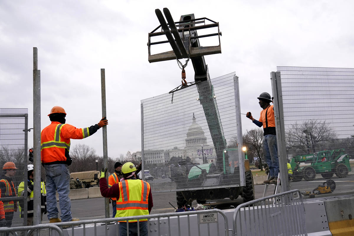 Workers install security fencing near the U.S. Capitol in Washington, Friday, Jan. 15, 2021, ah ...
