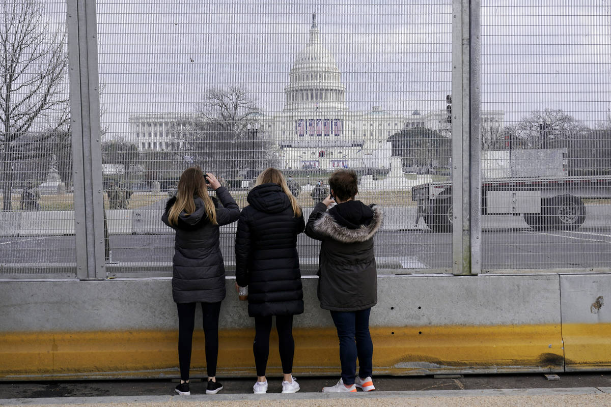 People take photos through the extensive security surrounding the U.S. Capitol in Washington, F ...