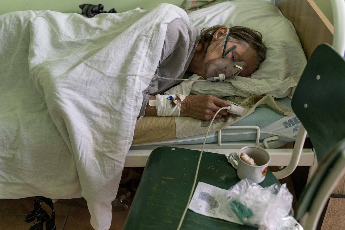 A patient with coronavirus breathes wearing an oxygen mask in an intensive care unit at the hos ...