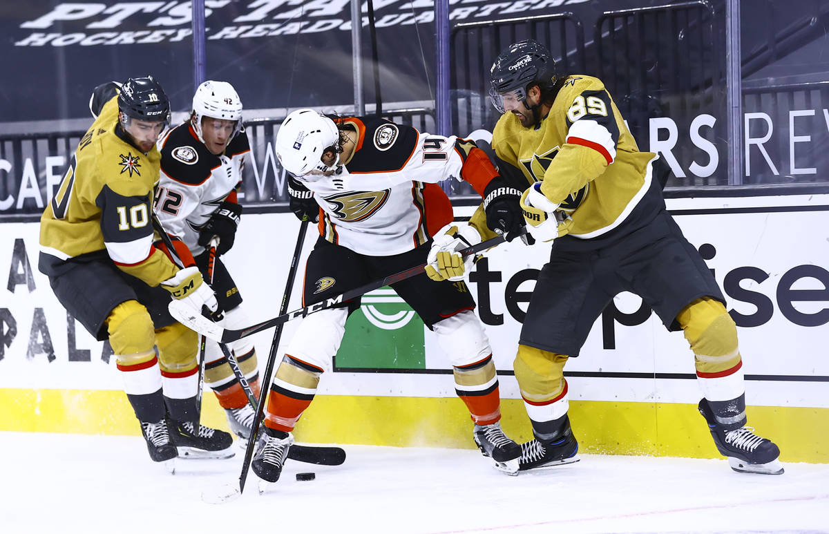 Golden Knights center Nicolas Roy (10) and right wing Alex Tuch (89) try to gain possession of ...