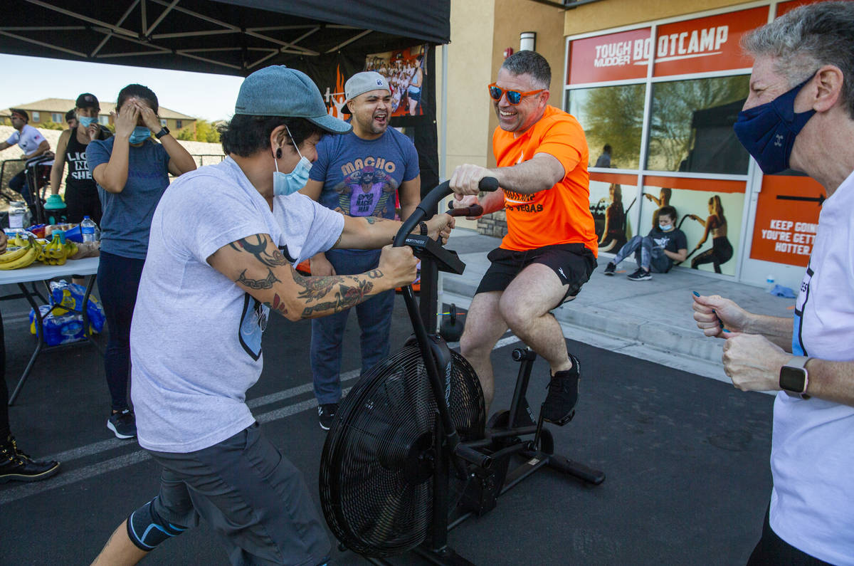 Co-owner Cory Drumright, center, is pumped up by Ron Bondoc,left, and others as he pedals some ...