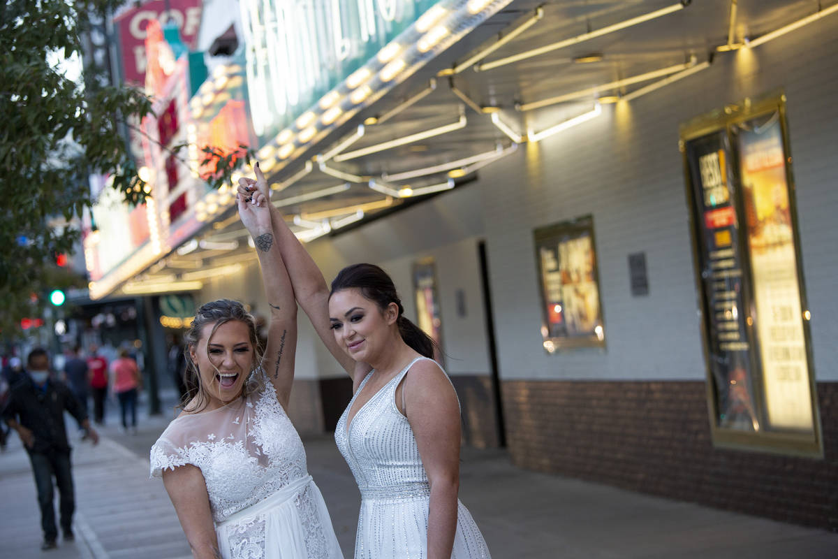 Newlyweds Brittnee Austin, left, and Kirby Kraeymer-Austin pose for their wedding photographer, ...