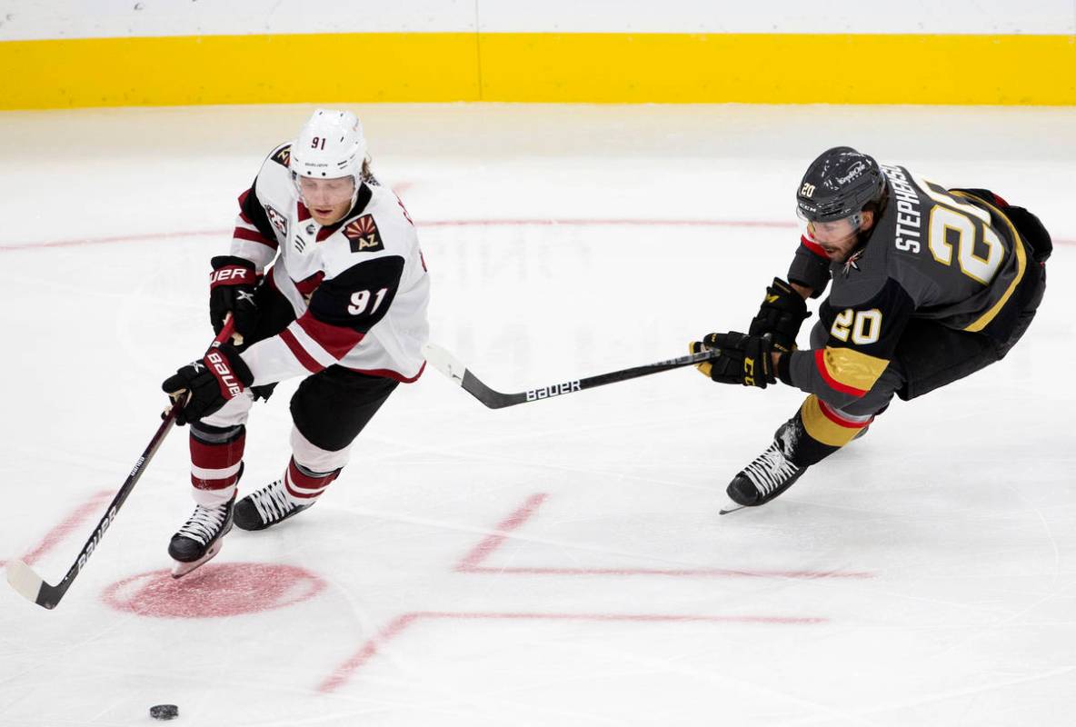 Golden Knights' center Chandler Stephenson (20) eyes the puck alongside Arizona Coyotes' center ...