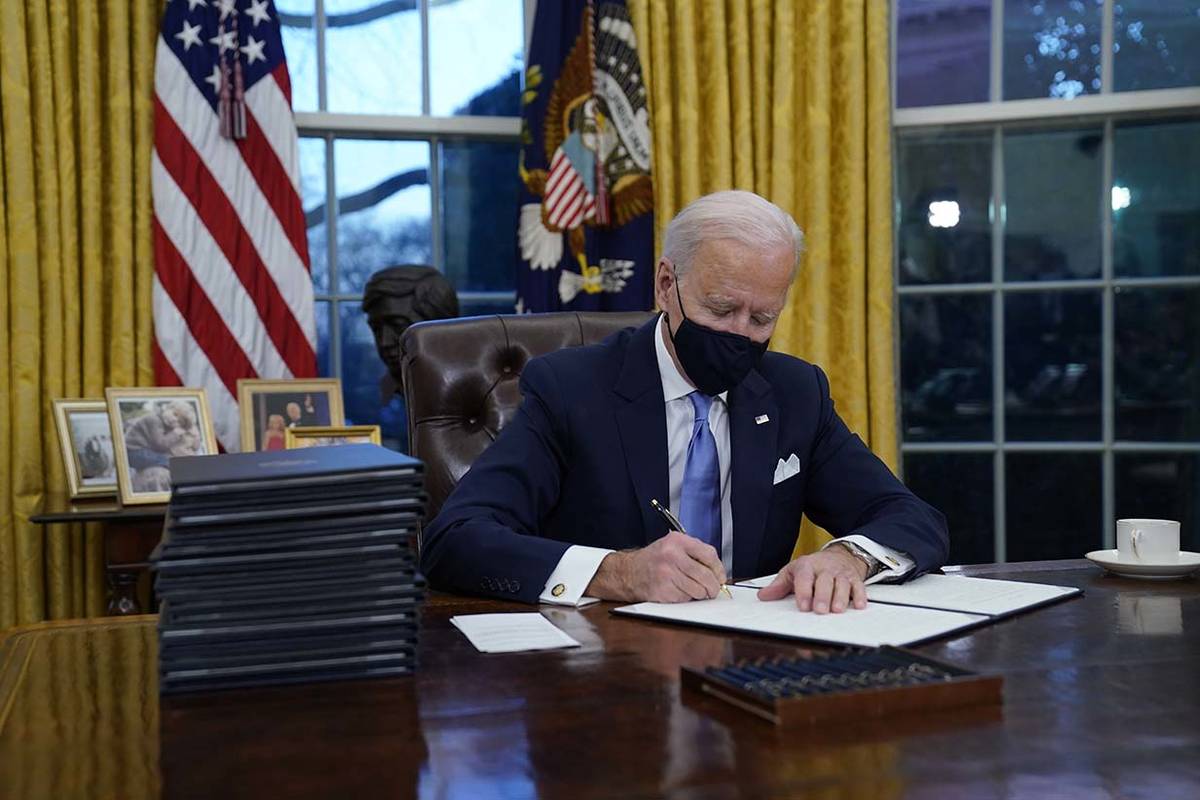 President Joe Biden signs his first executive orders in the Oval Office of the White House on W ...