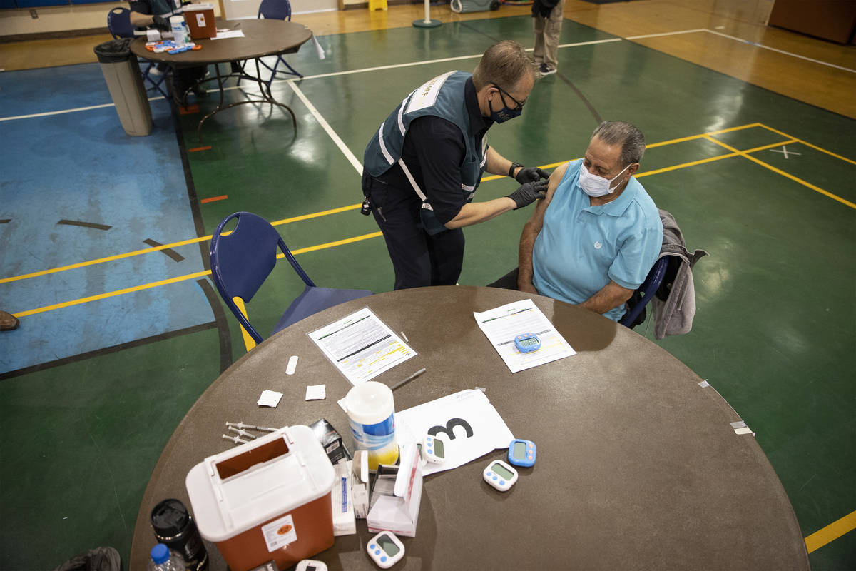 Richard Martinez, 73, right, receives the COVID-19 vaccine from Steve Soderberg, fire engineer ...