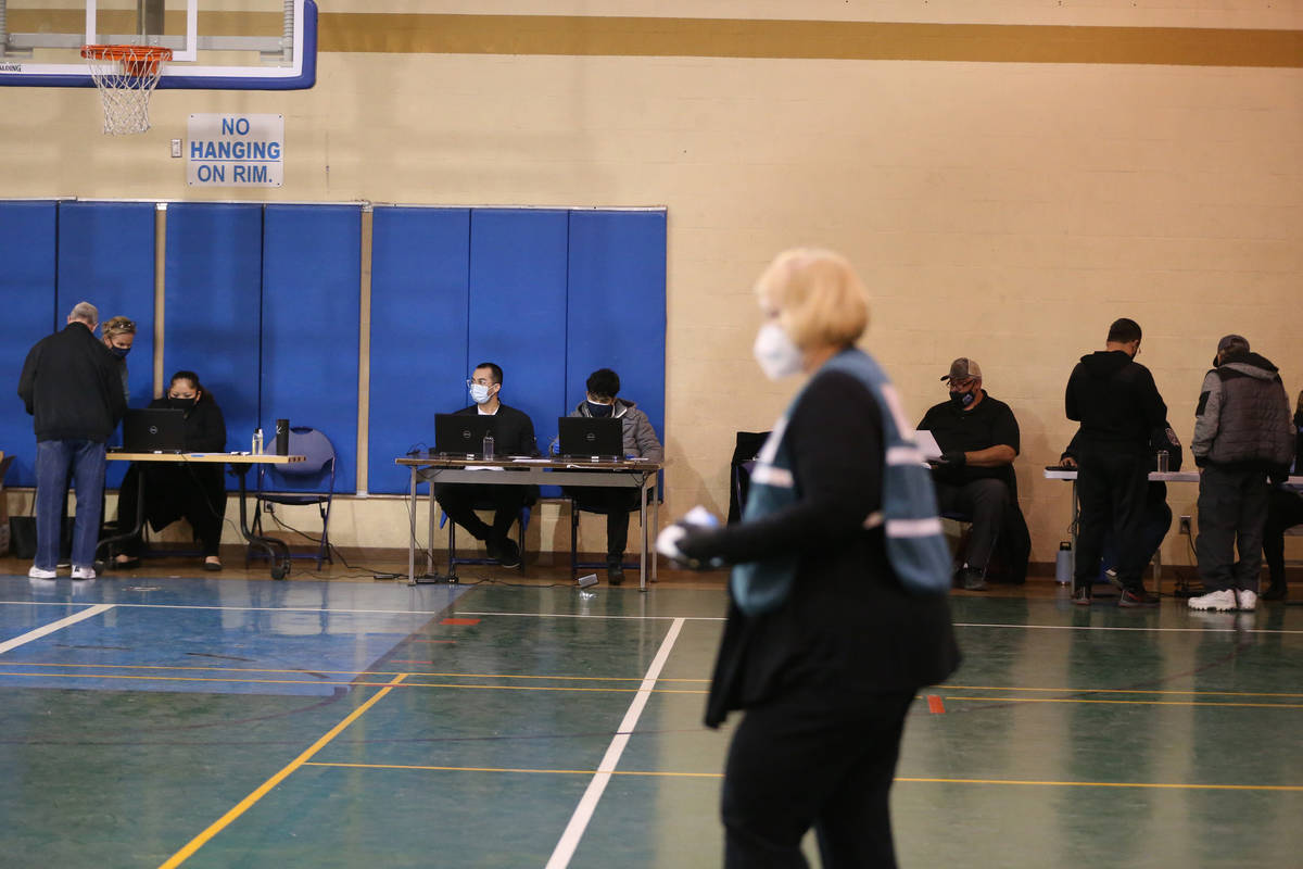 Staff members help people create appointments for their second dose of the COVID-19 vaccine at ...