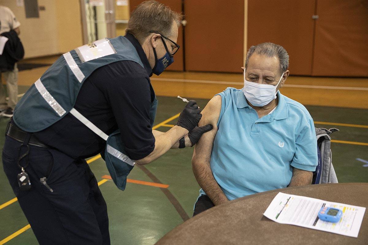 Richard Martinez, 73, right, receives the COVID-19 vaccine from Steve Soderberg, fire engineer ...