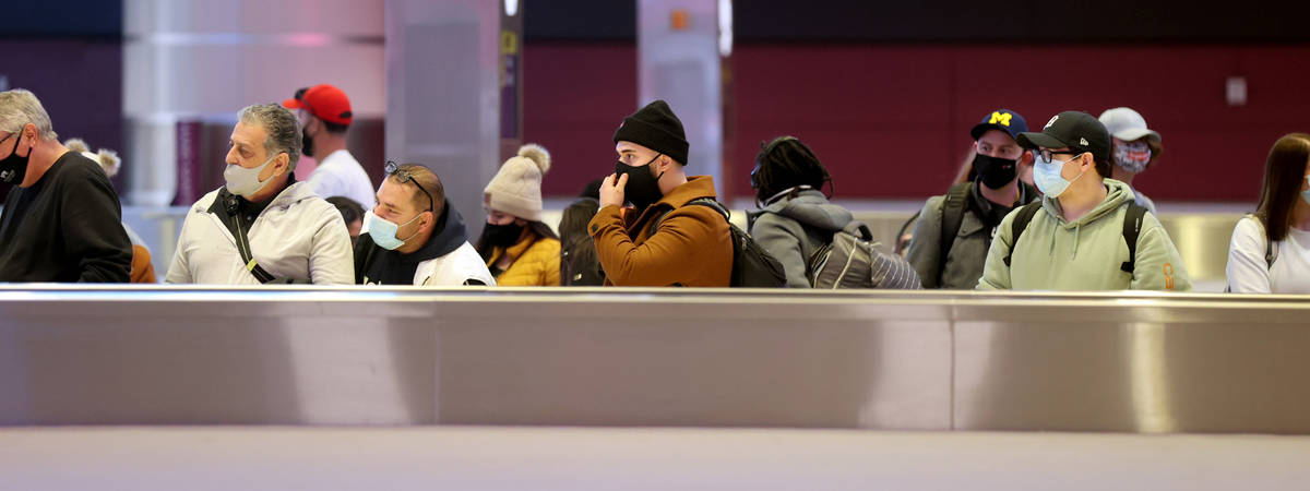Masked travelers wait to retrieve their luggage in baggage claim Terminal 1 at McCarran Interna ...