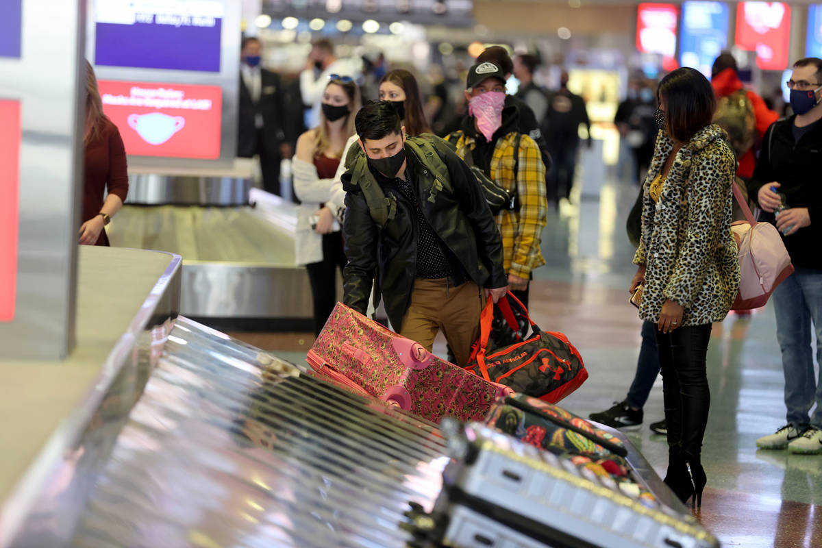 Masked travelers retrieve their luggage in baggage claim Terminal 1 at McCarran International A ...