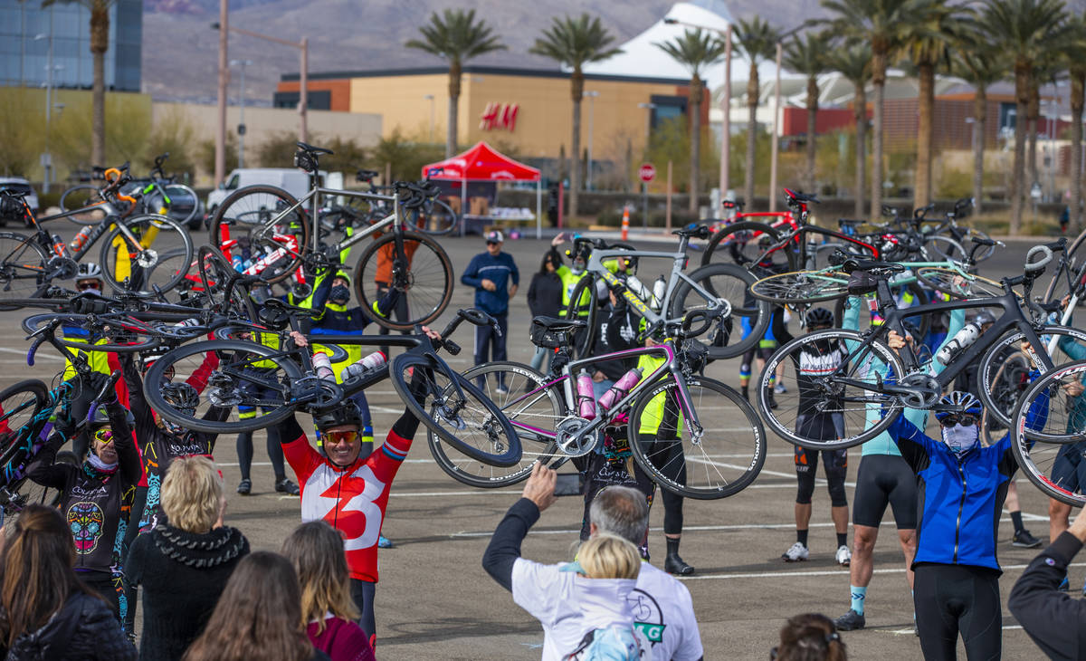 Cyclists hold their bikes over their heads as friends and family gather to honor the five cycli ...