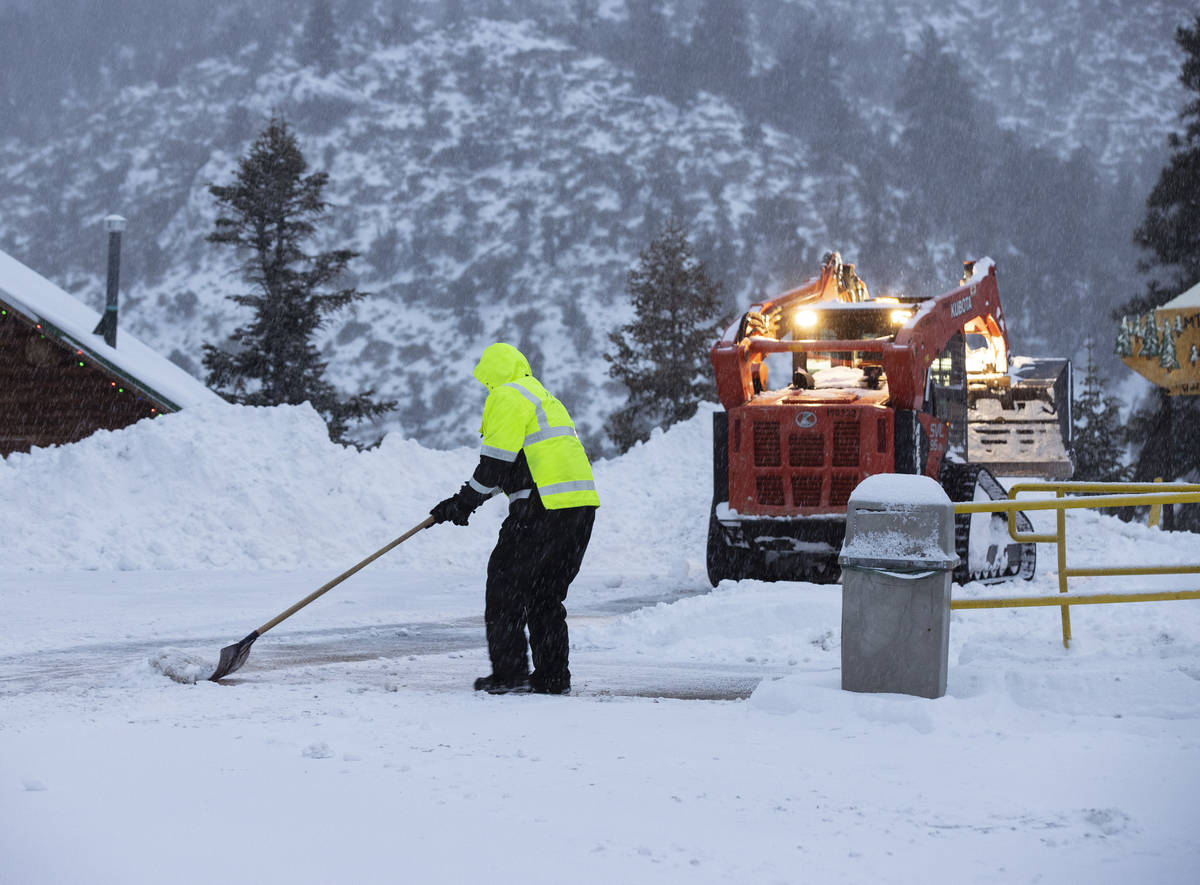 Workers remove snow from the parking lot at The Charleston Lodge, on Monday, Jan. 25, 2021, in ...