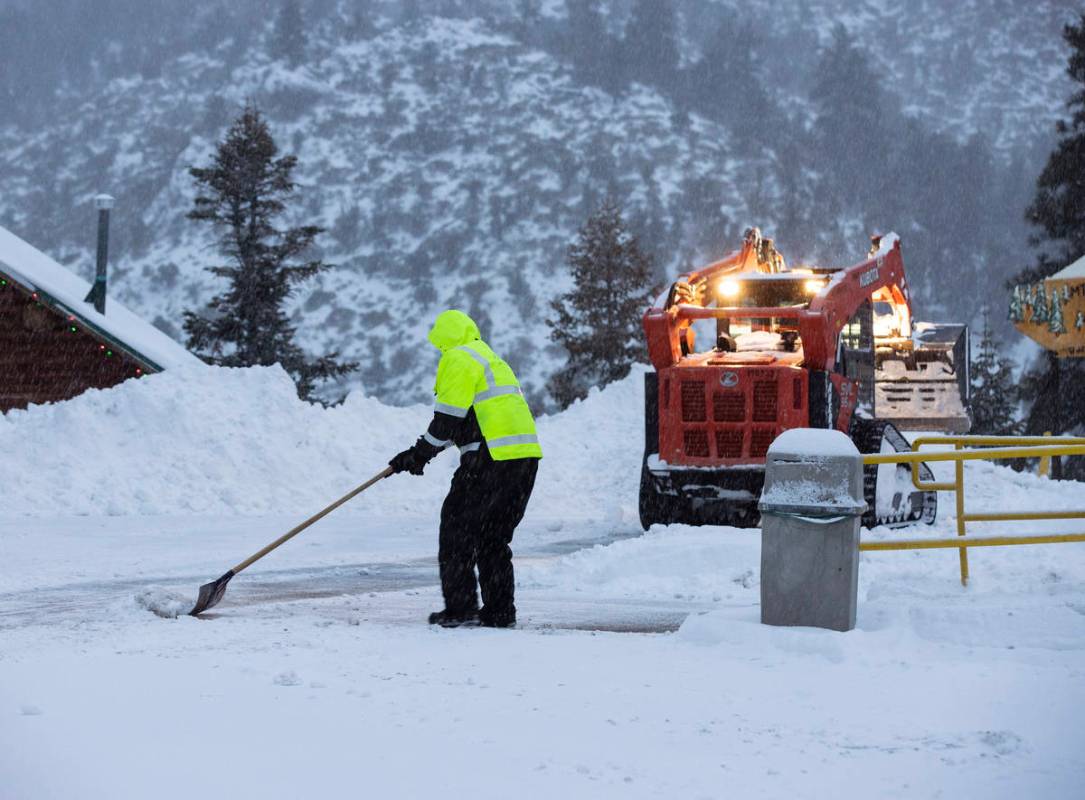 Workers remove snow from the parking lot at The Charleston Lodge, on Monday, Jan. 25, 2021, in ...