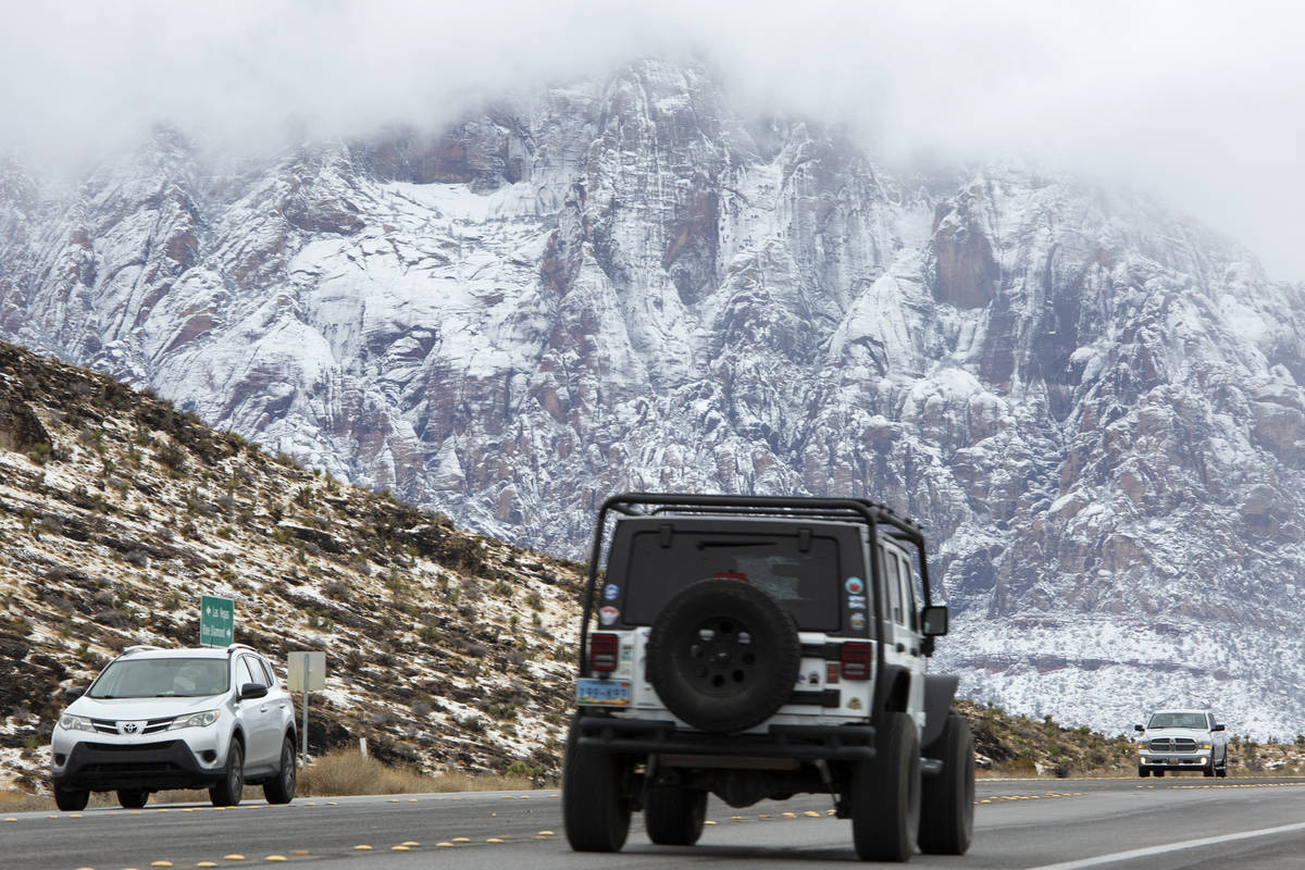 Visitors drive through Red Rock National Conservation Area as snow covers the mountains on Mond ...