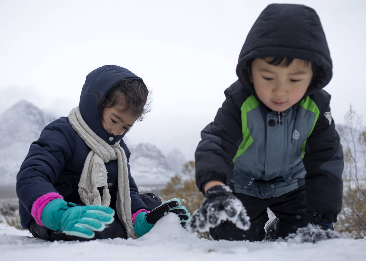 Iliana Lopez, 6, left, and her brother Sasha Lopez, 4, build a snow mountain to match the mount ...