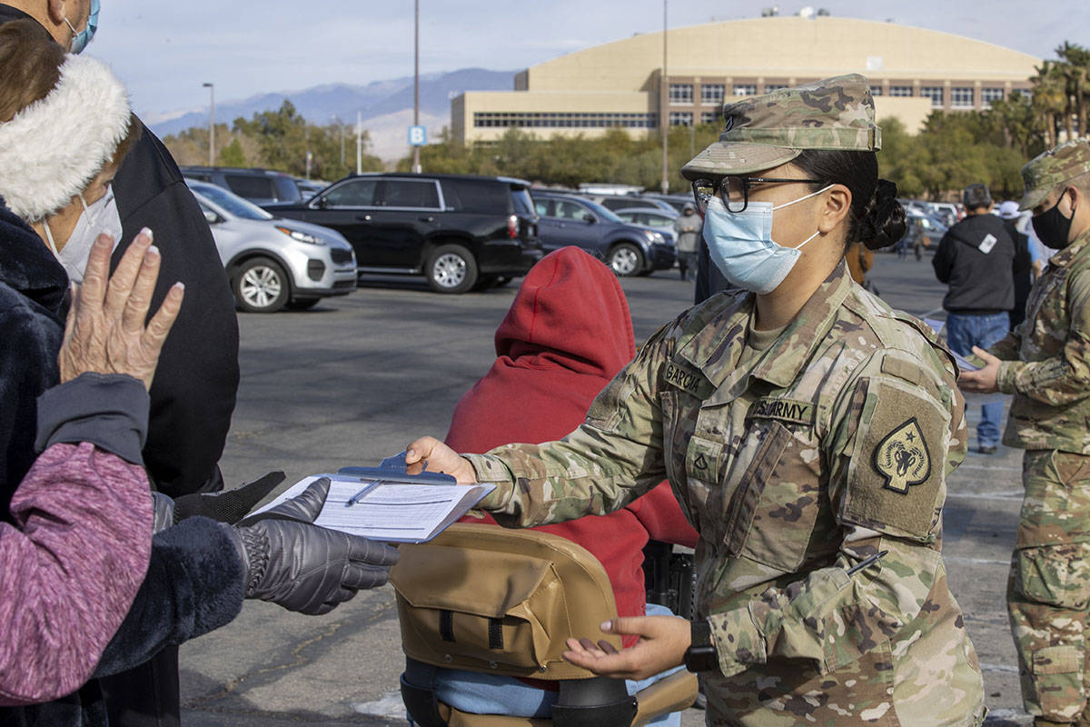 PFC Wendy Garcia passes out paperwork as people wait in line to enter the Cashman Center for CO ...