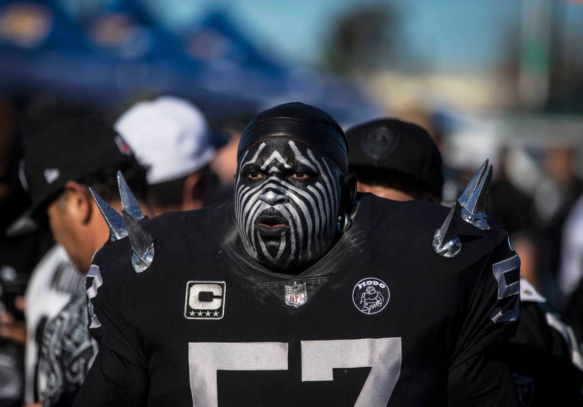 Raiders super fan Wayne Mabry, known as "Violator," walks through a tailgate outside ...