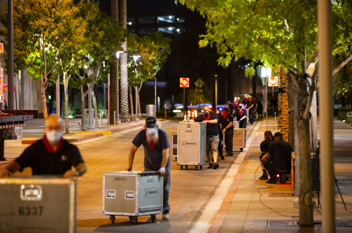 Entertainment workers push road cases around The Smith Center as it turns red for the "Red ...