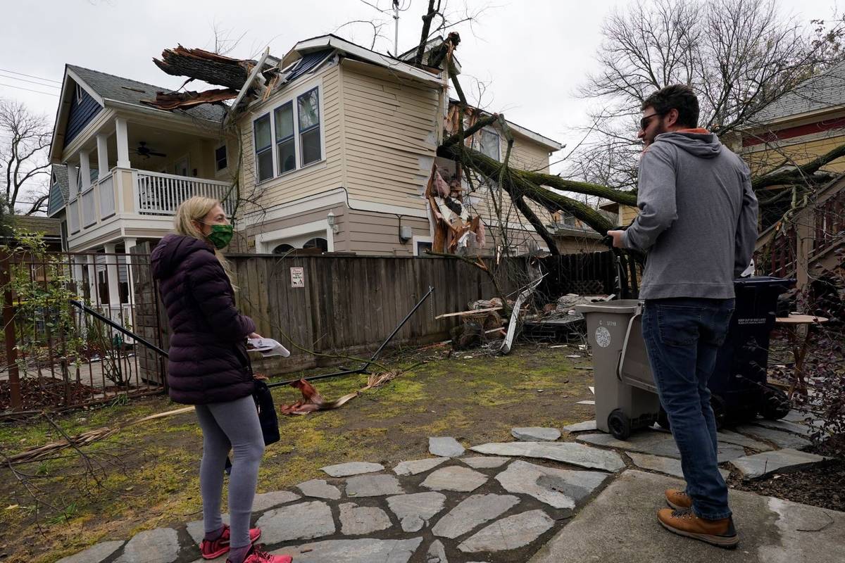 Amy Lilly talks with neighbor Eric Rose as they look over her home damaged by a tree limb that ...