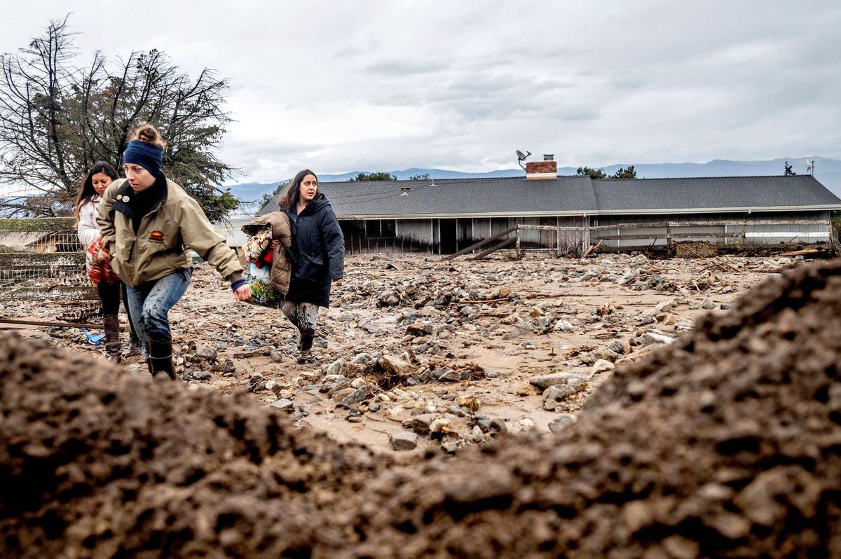 Hana Mohsin, right, carries belongings from a neighbor's home which was damaged in a mudslide o ...