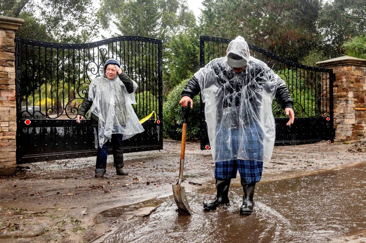 Alex, left, and Aron Moreno work to divert water from their property as heavy rains fall in Sal ...