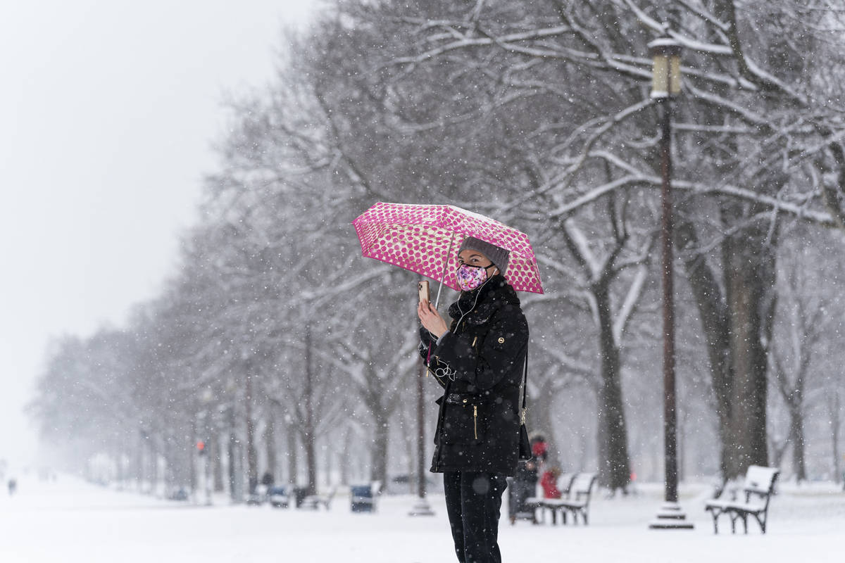 Paulina Lozano speaks with her parents by phone, as snow falls on the National Mall, Sunday, Ja ...