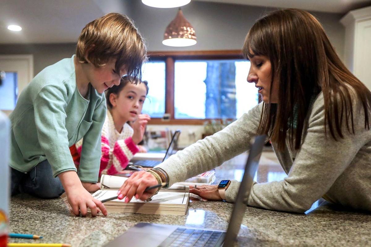 Max Millard, left, colors with mom Kim, right, while sister Mia looks on as dinner cooks in the ...