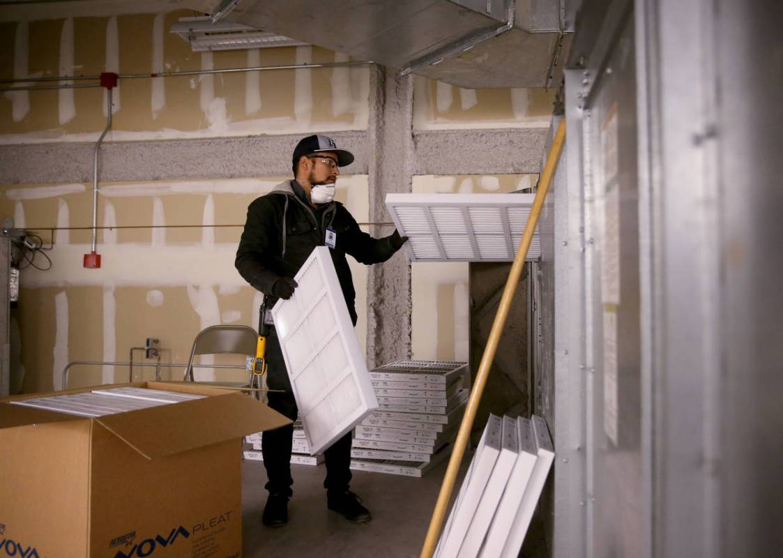 Clark County School District Building Engineer IV Juan Avila changes filters on the heating, ve ...