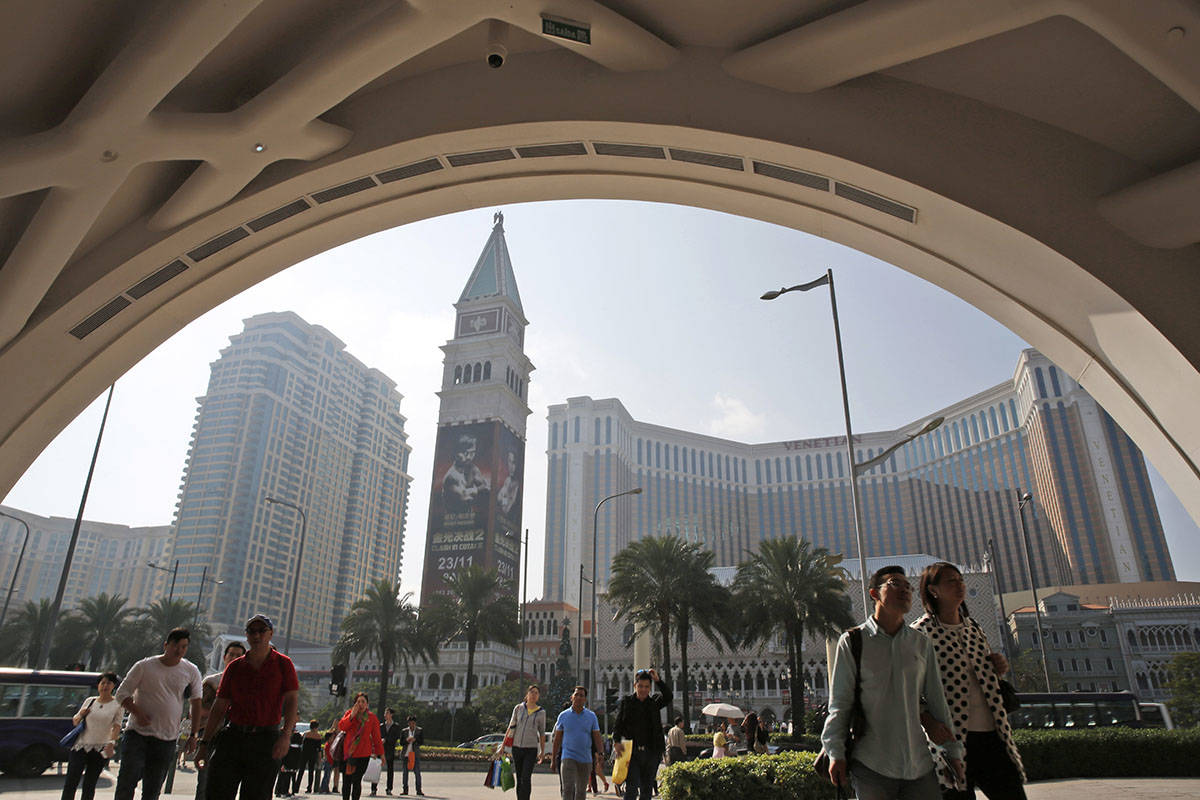 In this photo taken Nov. 23, 2014, visitors walk across the road in front of the Venetian Macao ...