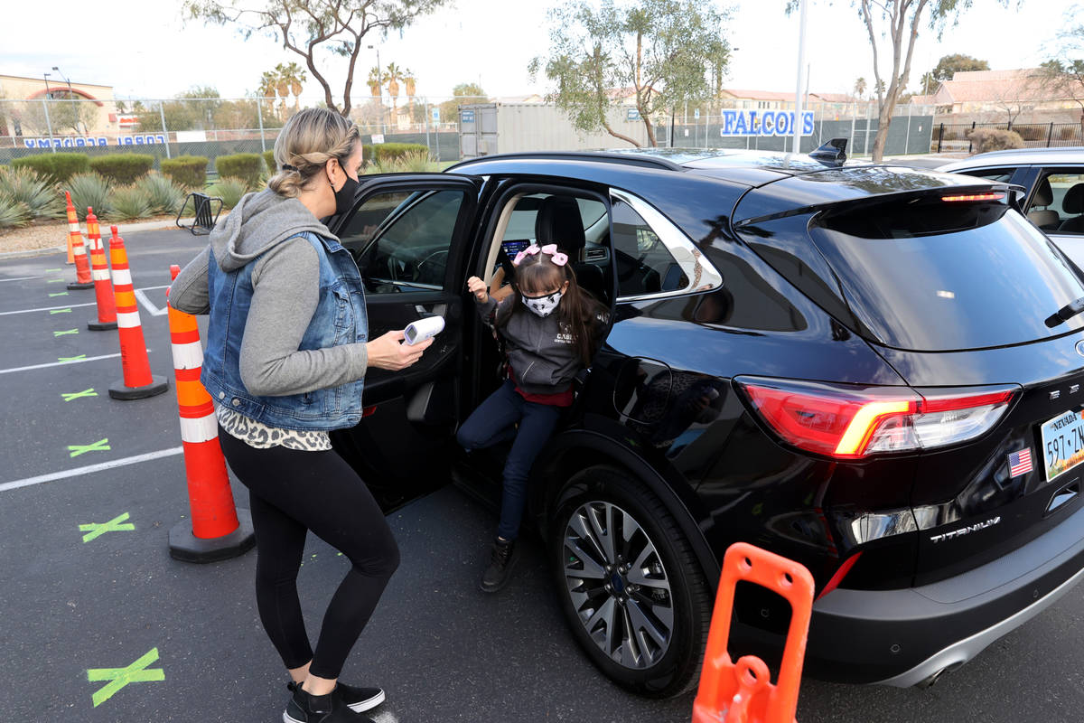 Staff member Amanda Nikolopoulos prepares to take the temperature of student Mason Bachmura, 7, ...