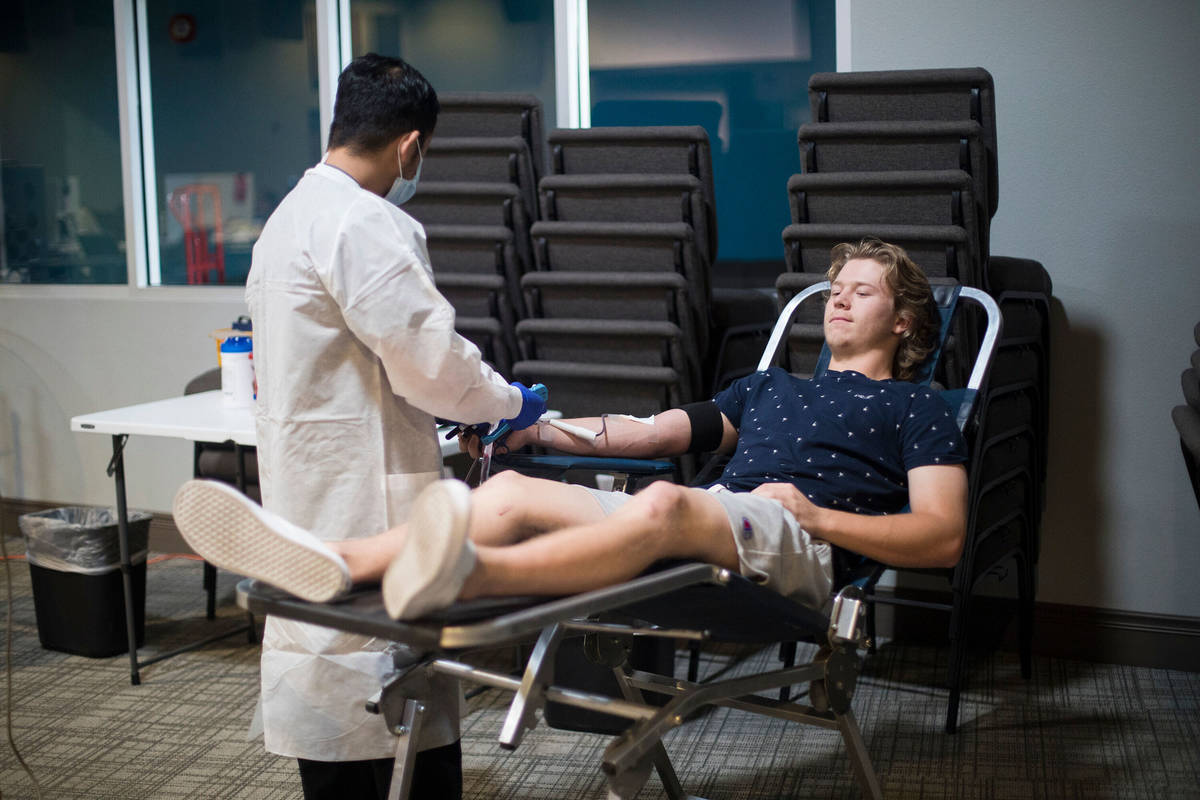 In this April, 12, 2020, file photo, Ernesto Perez, a phlebotomist tech and supervisor, helps W ...