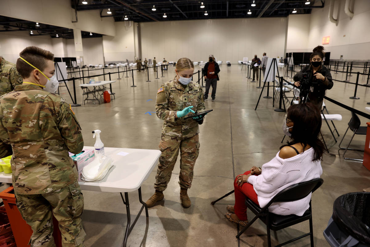 Nevada National Guard Spc. Taylor Reynolds, center, checks in Barbara Moore, 71, of Las Vegas, ...