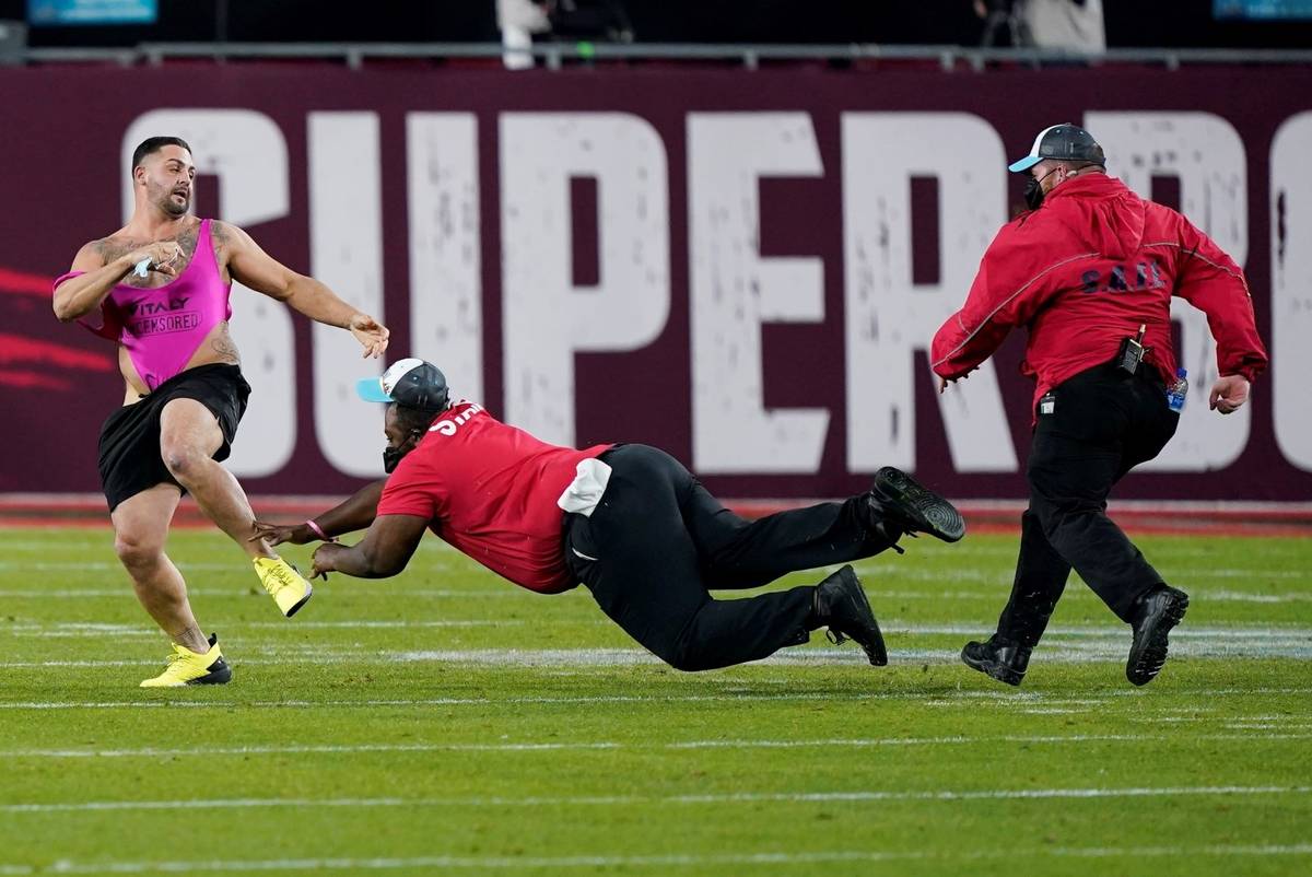 Security tries to grab a fan on the field during the second half of the NFL Super Bowl 55 footb ...