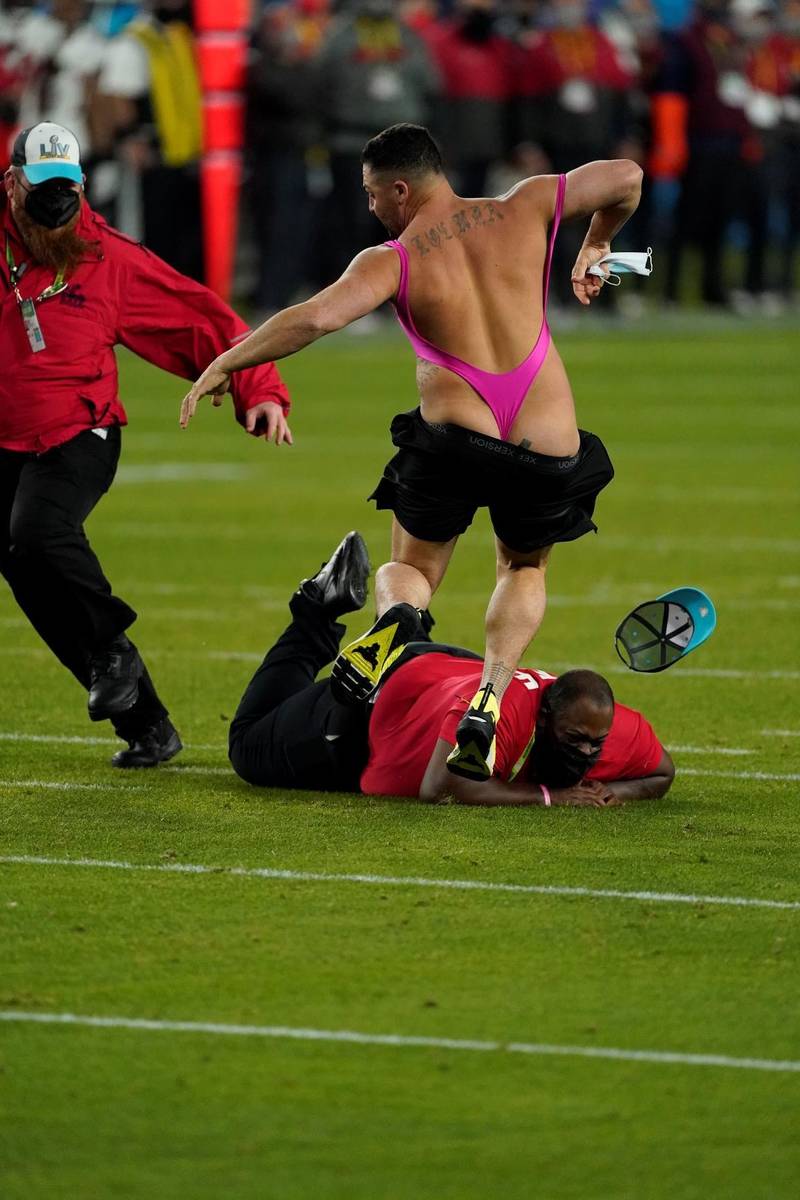 Security tries to grab a fan on the field during the second half of the NFL Super Bowl 55 footb ...